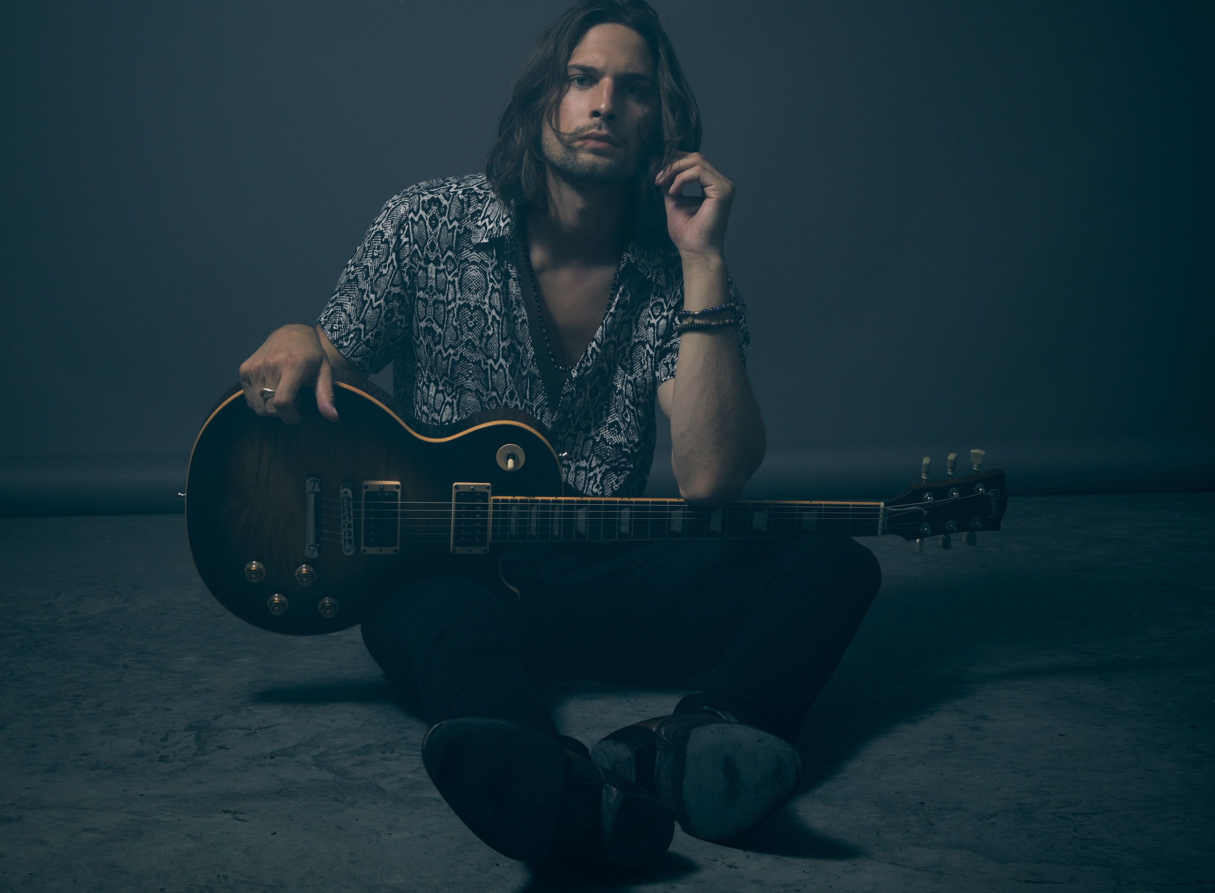 David Myhre studio portrait sitting with guitar